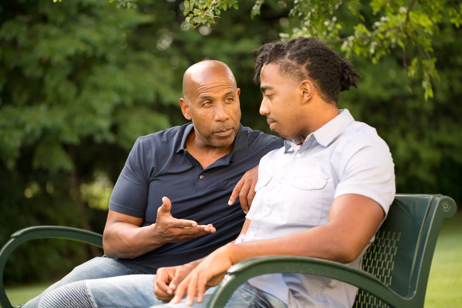 One man listening carefully to another on a park bench